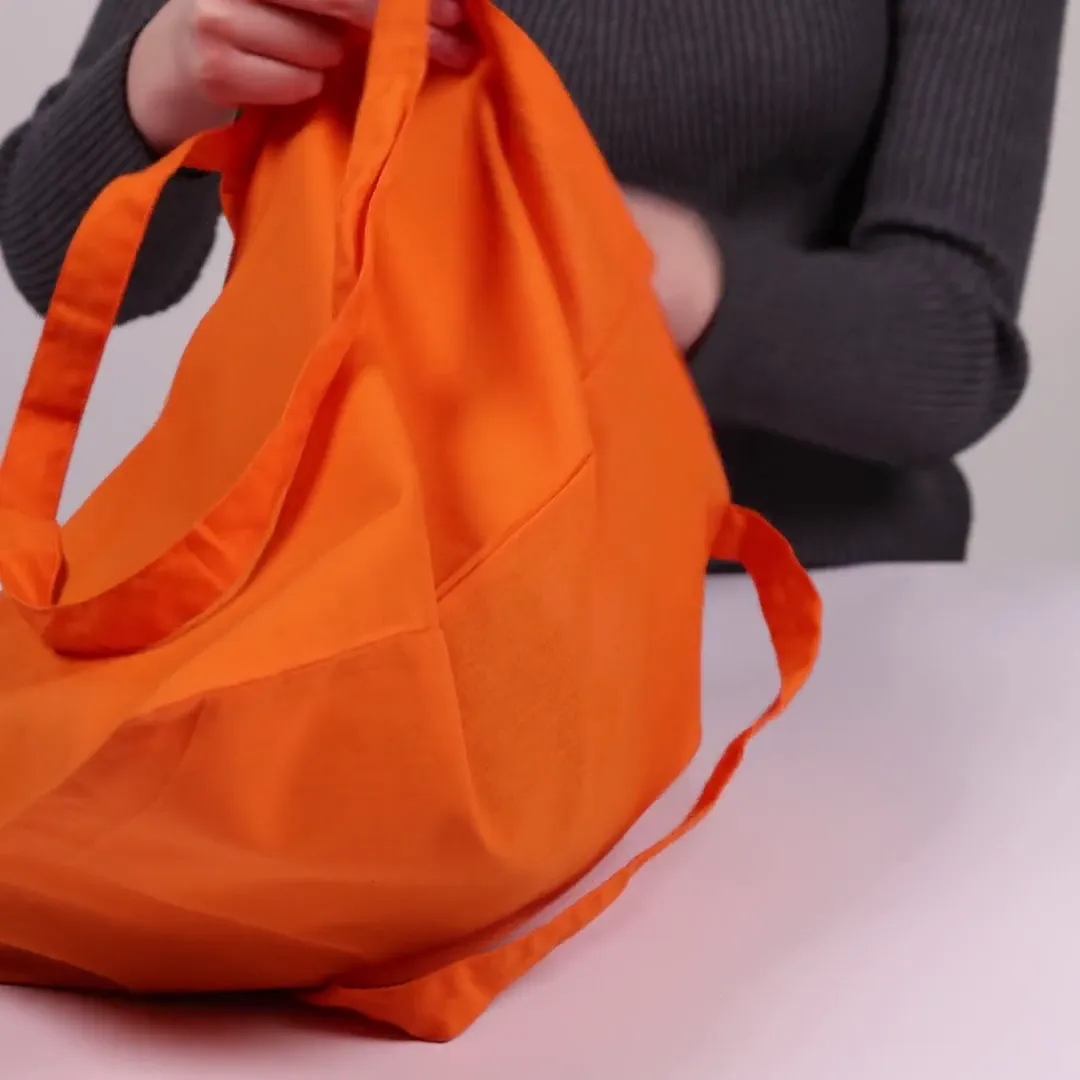 Bomullskasse, 140 g/m², visad av en person i produktvideon – orange