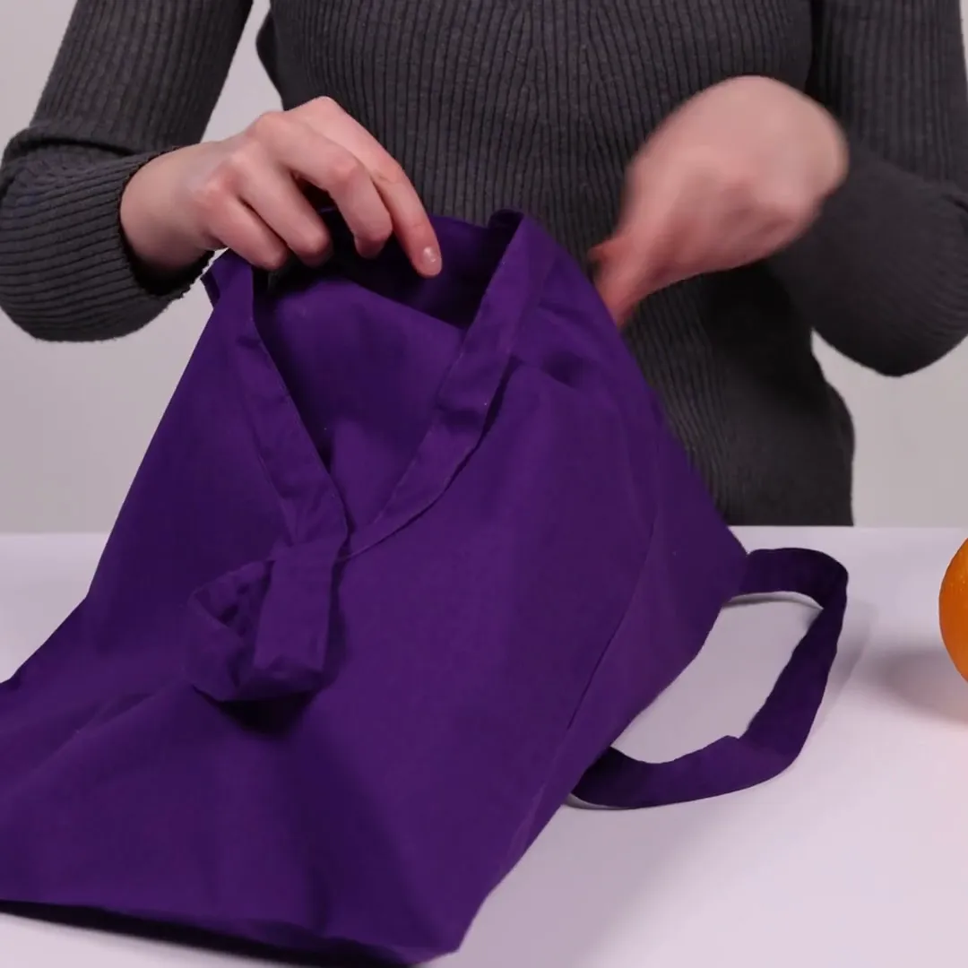 Bomullskasse, 140 g/m², visad av en person i produktvideon – violett