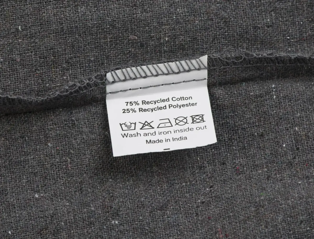 Tygkasse – etikett med 75 % återvunnen bomull, 25 % återvunnen polyester och tvättsymboler.
